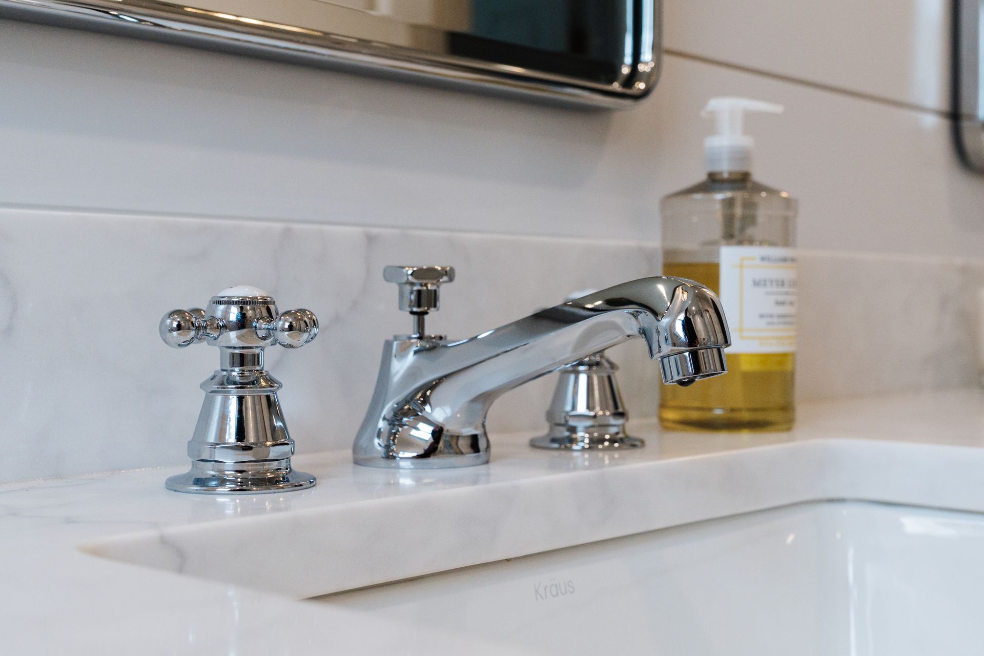 A bathroom sink with a faucet and a soap dispenser