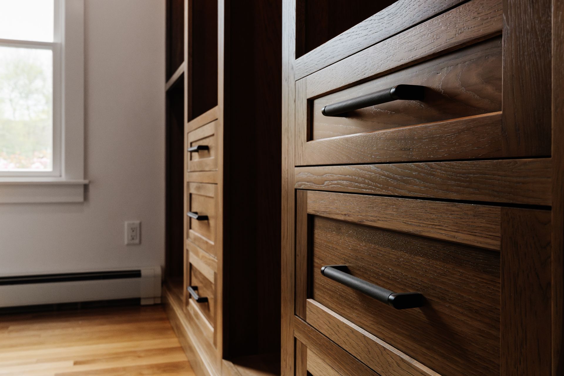 A room with wooden cabinets and drawers and a window.