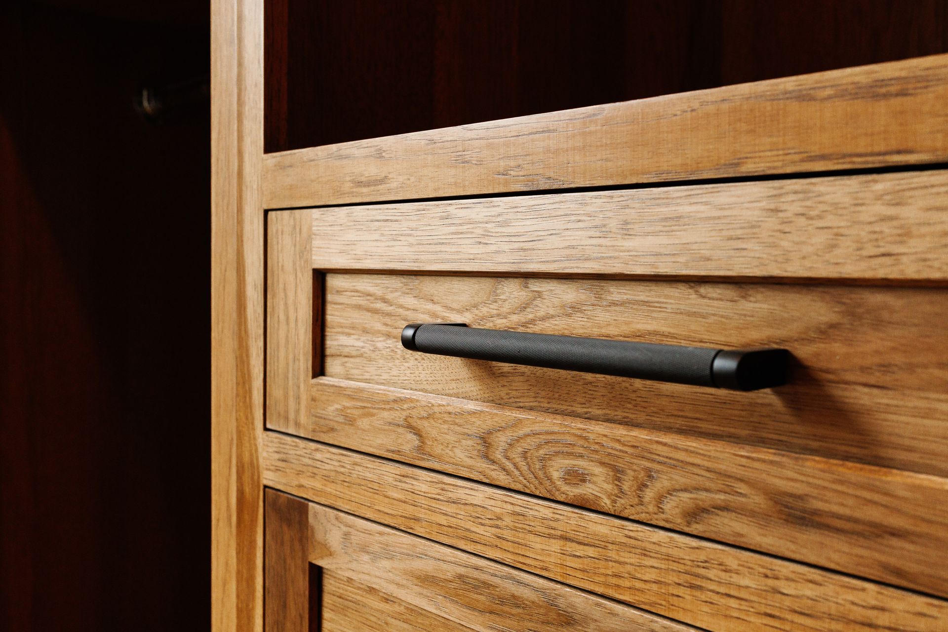 A close up of a wooden drawer with a black handle.