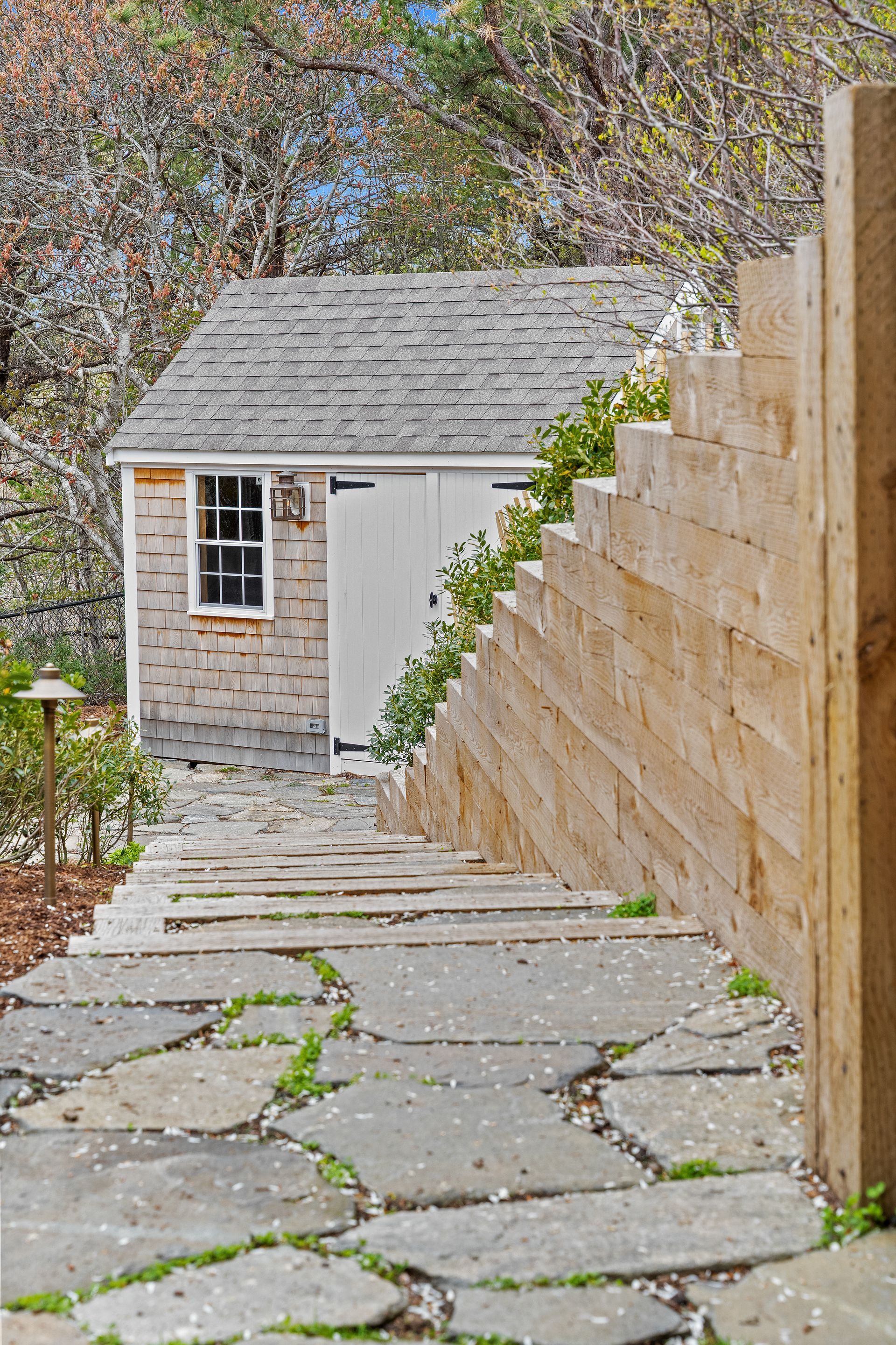 A stone path leading to a shed with stairs leading up to it.