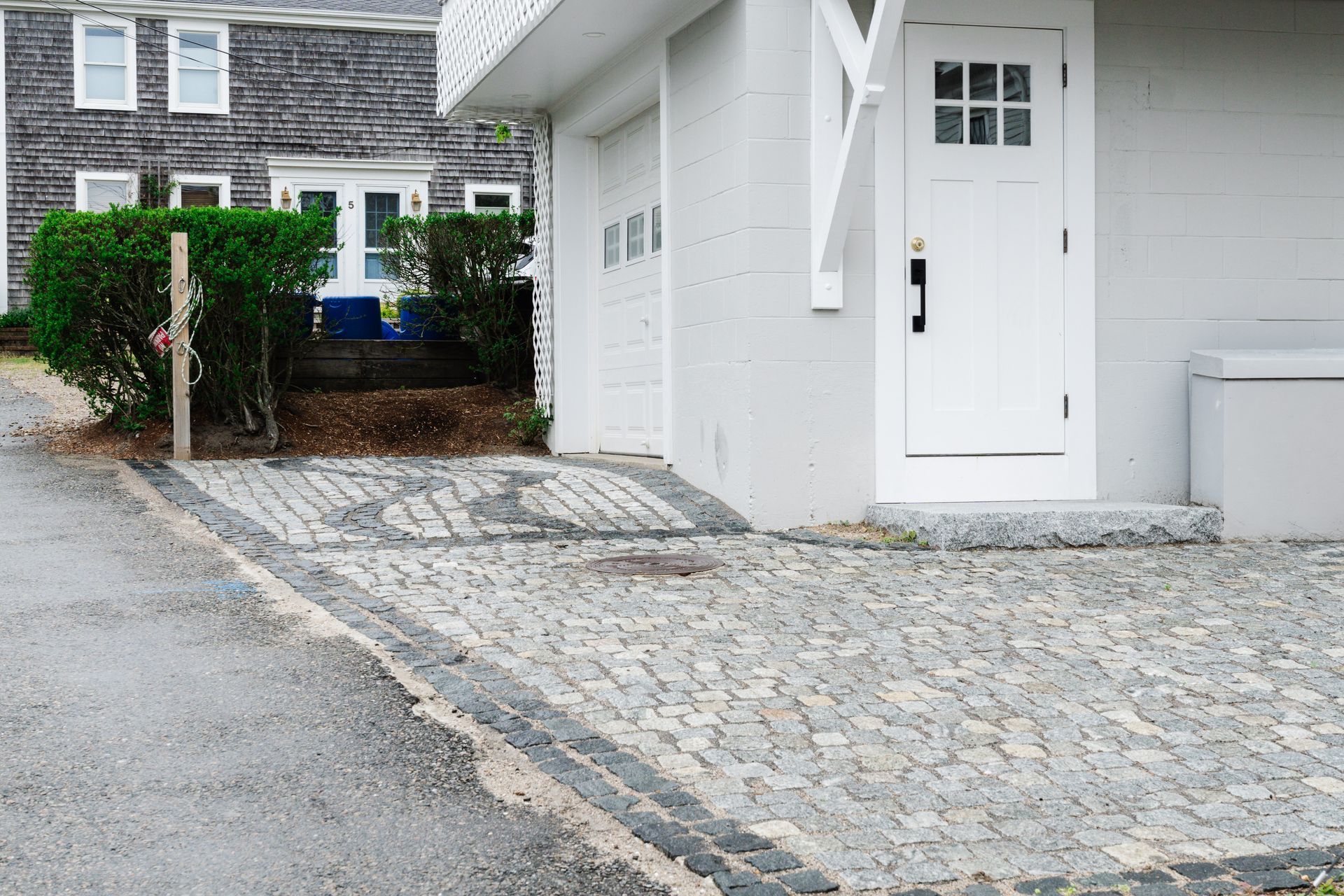 A white house with a cobblestone driveway in front of it