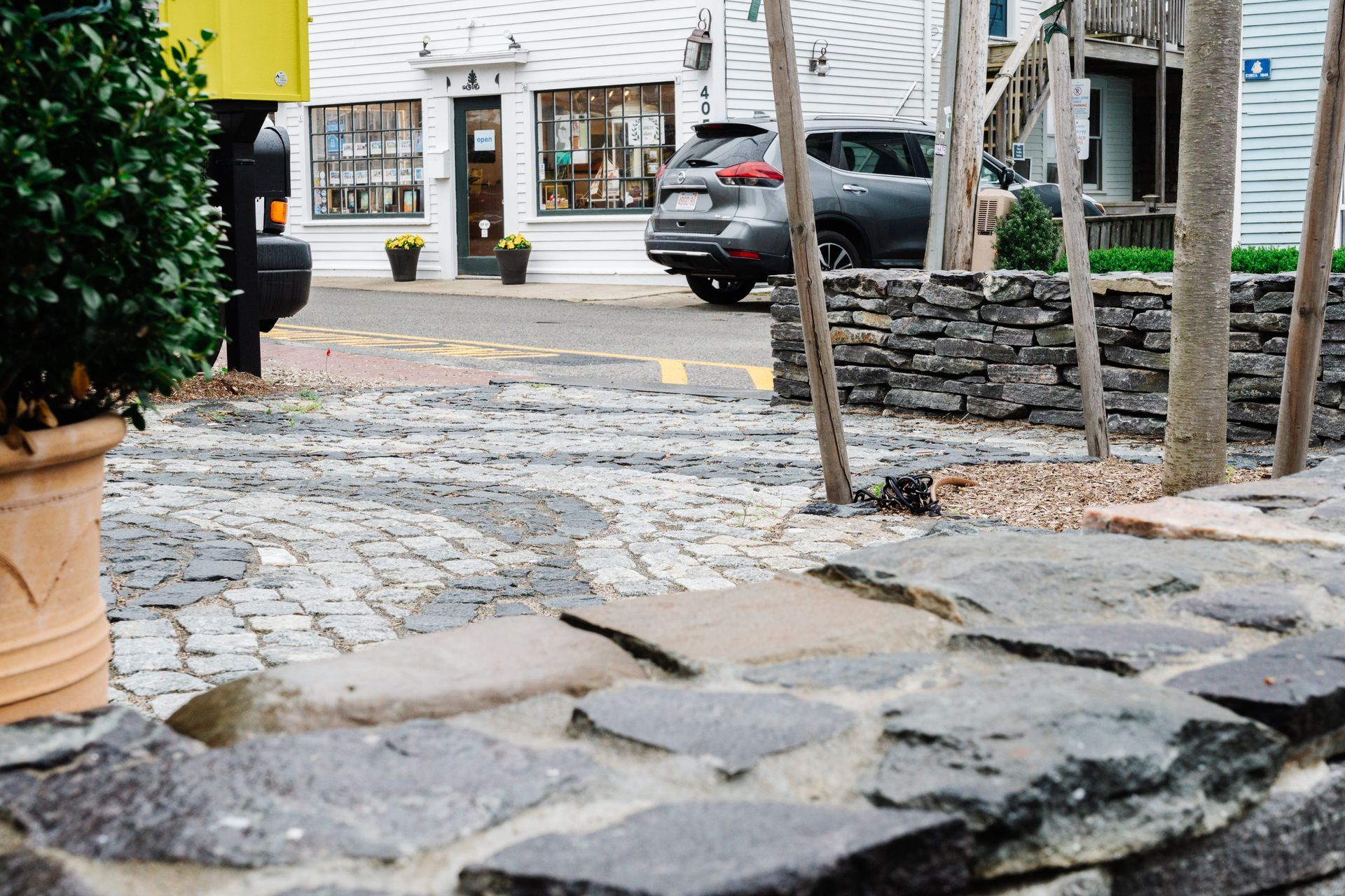 A car is parked on the side of the road next to a stone wall.