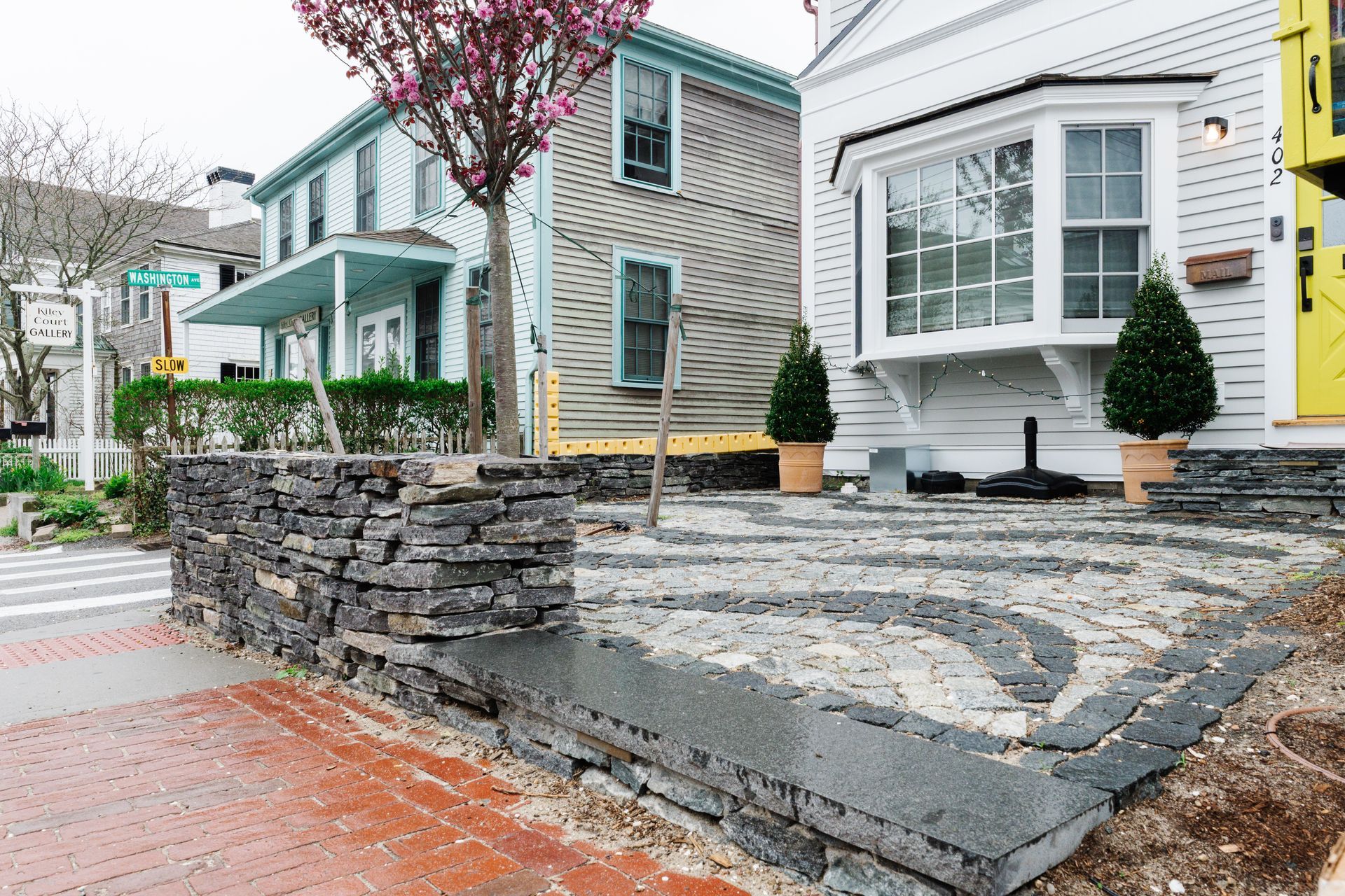 A house with a stone wall and stairs in front of it.