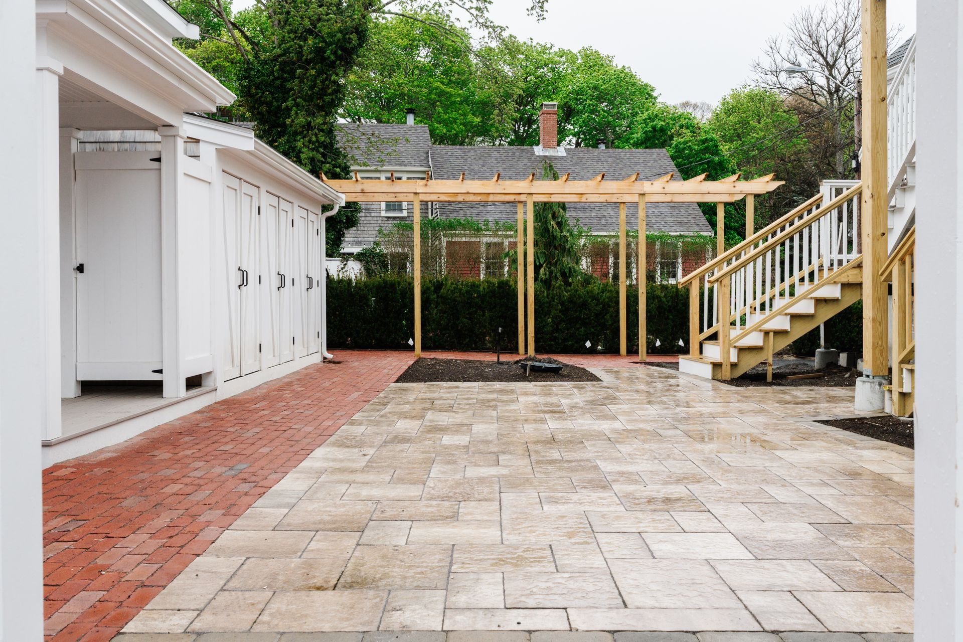 A patio with a pergola and stairs in front of a house