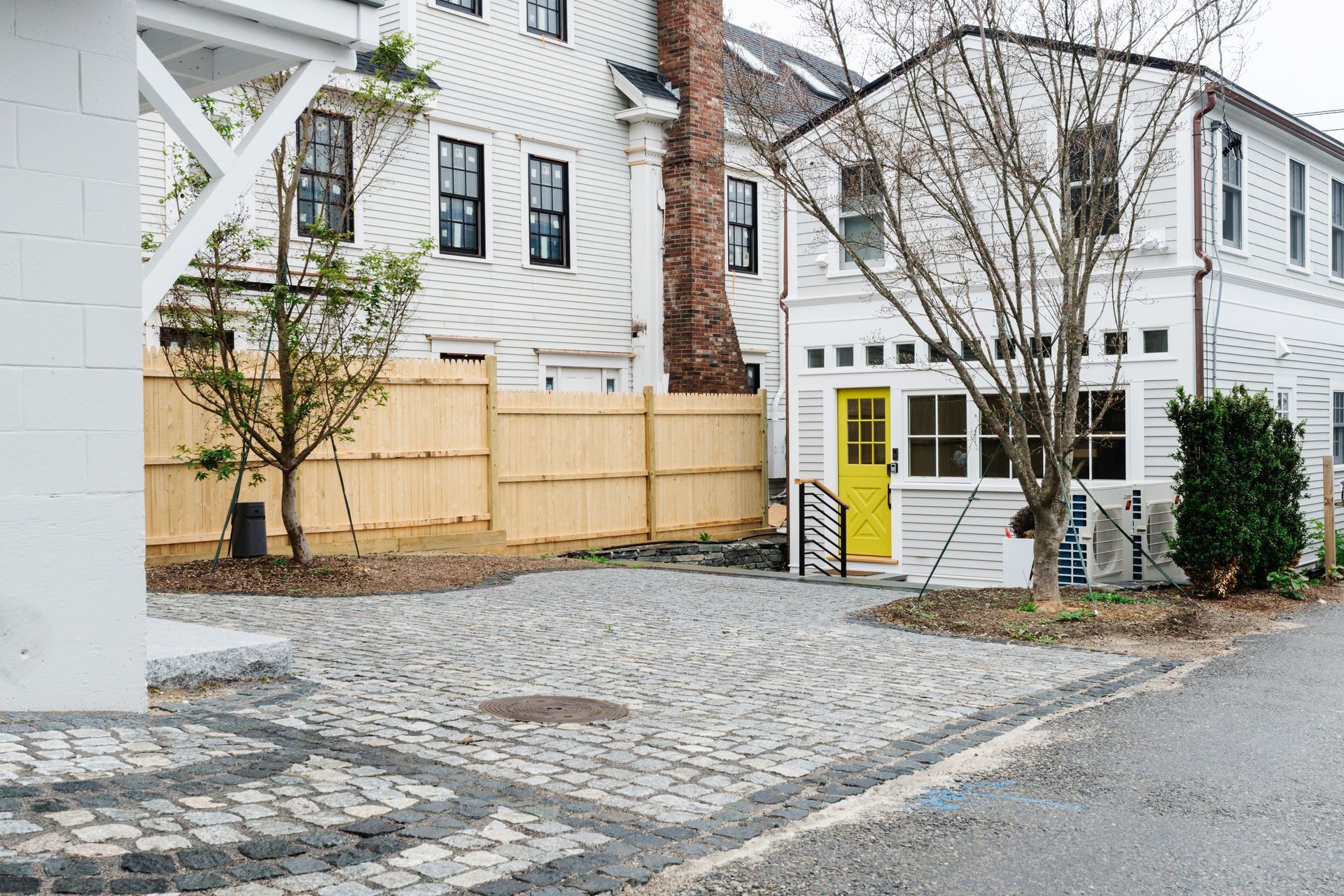 A white house with a yellow door and a wooden fence in front of it.