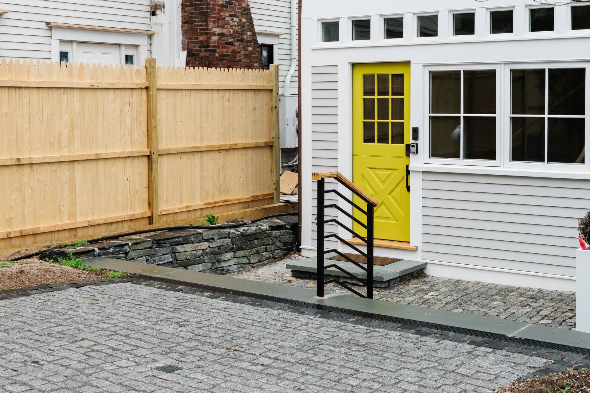 A white house with a yellow door and a wooden fence.