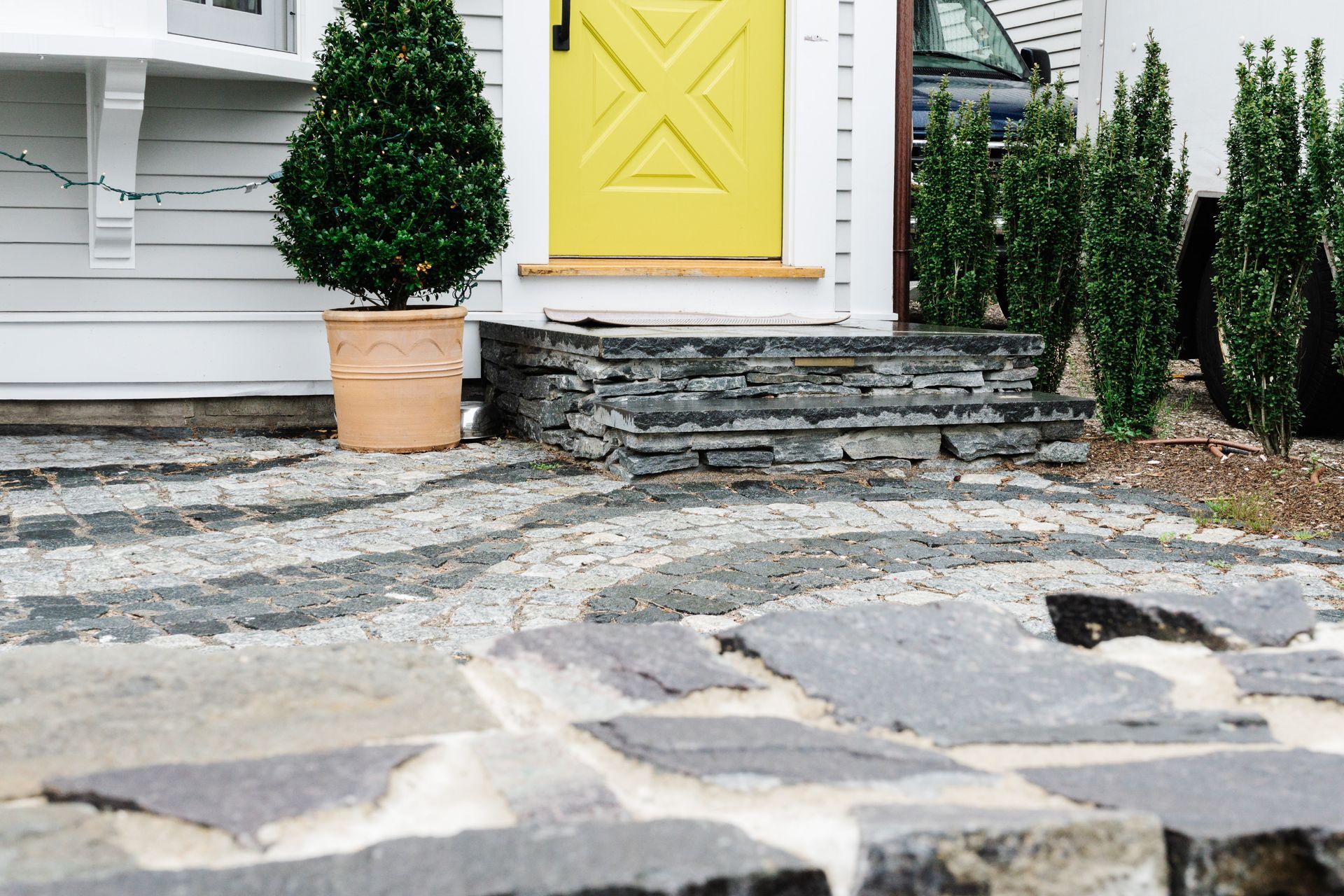 A yellow door with a cross on it is in front of a white house.