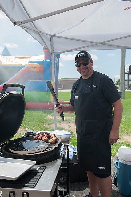 A man is standing in front of a grill holding a spatula.