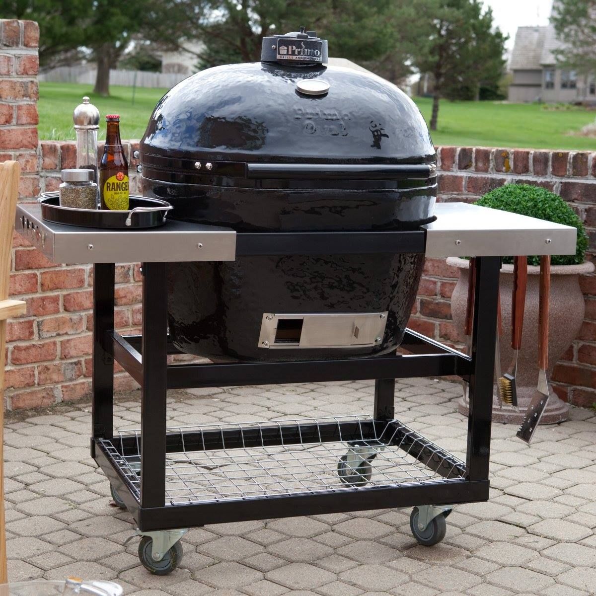 A large black grill is sitting on a cart on a brick patio