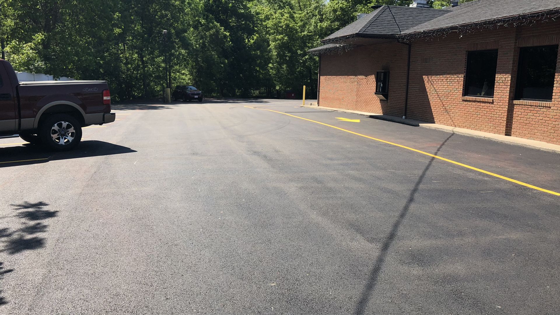Parking lot beside a brick building with a parked pickup truck and yellow curb line.