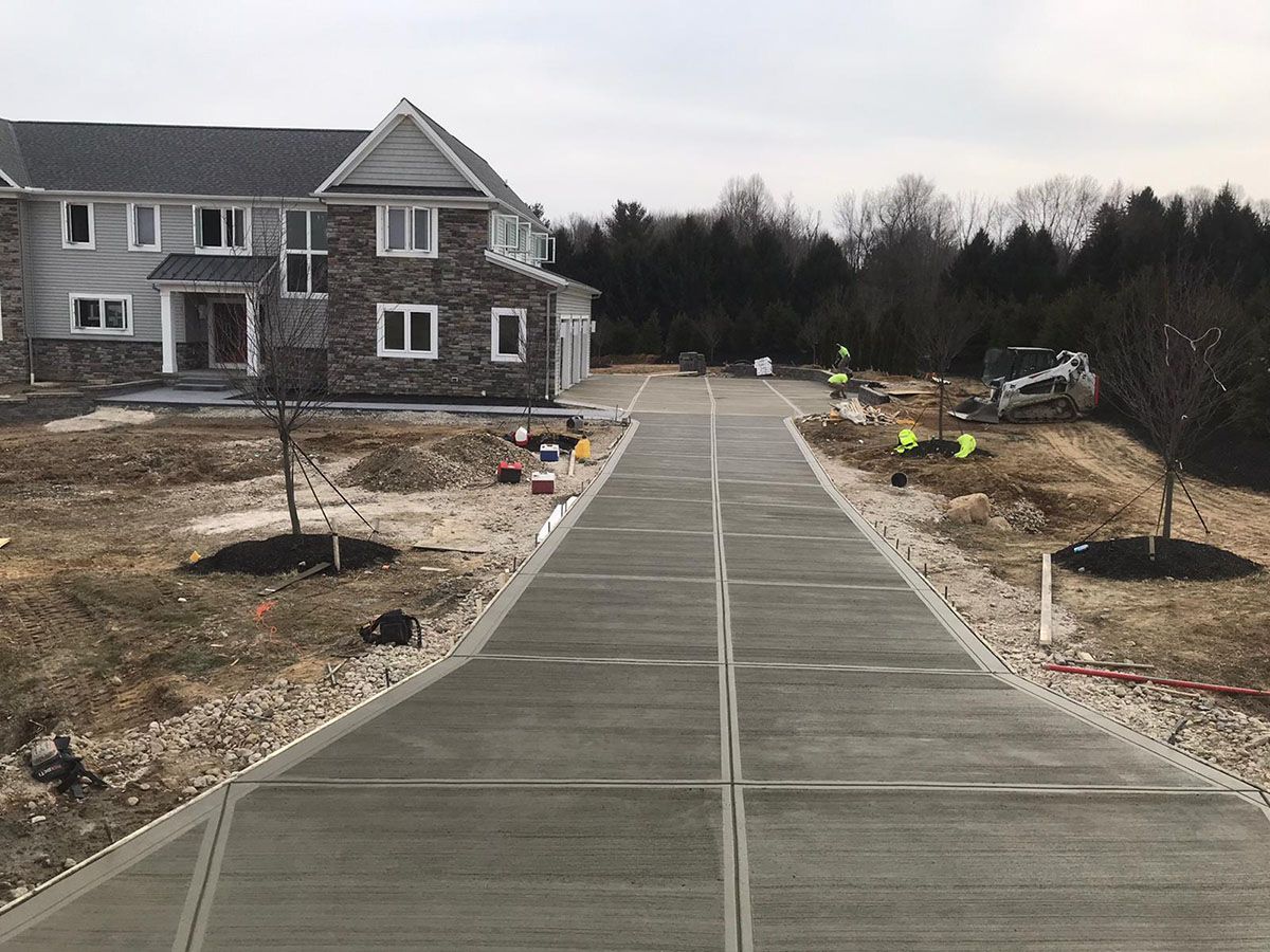 A concrete driveway leading to a large house.