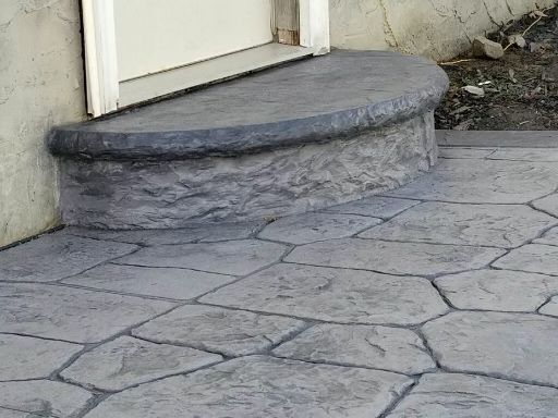 A concrete walkway with steps leading up to a door.