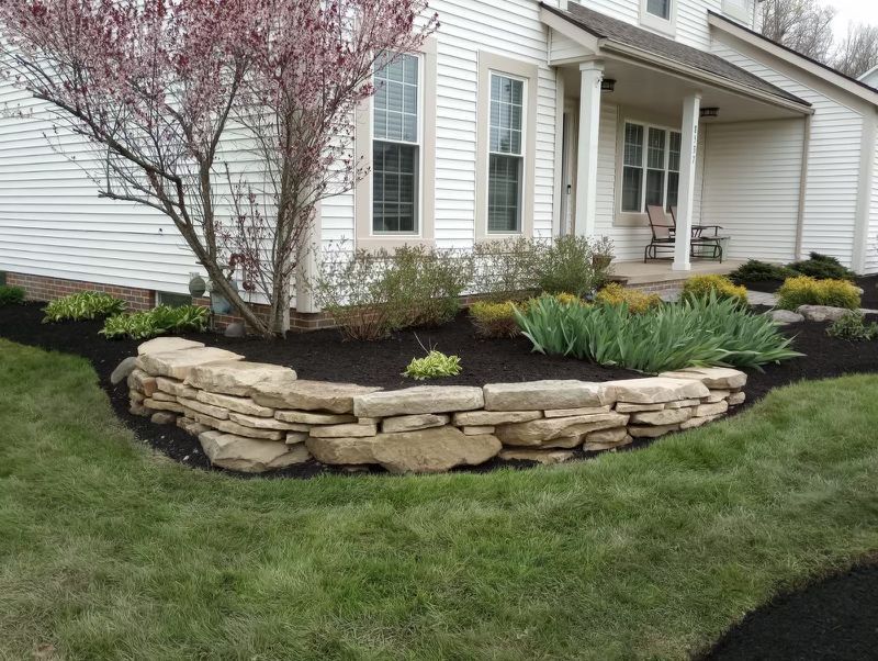 A white house with a stone wall in front of it