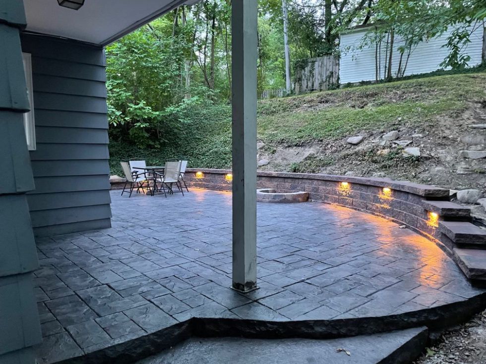 A patio with a table and chairs under a covered porch.