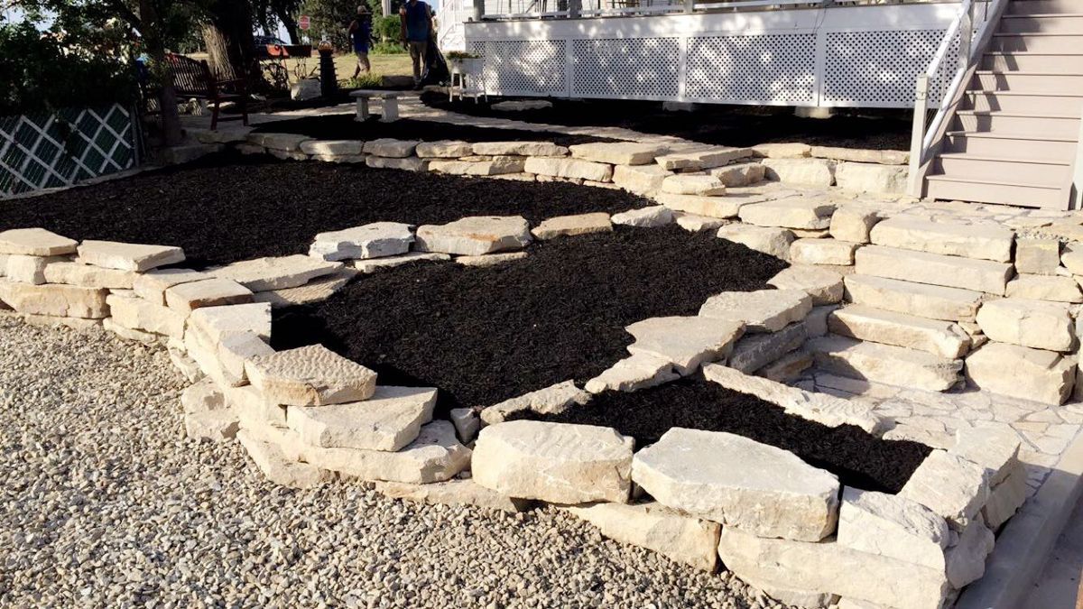 A white house with a stone wall in front of it