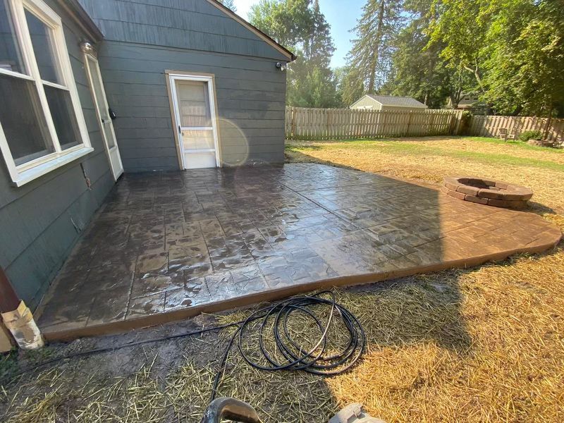 A patio with a fire pit in the backyard of a house.