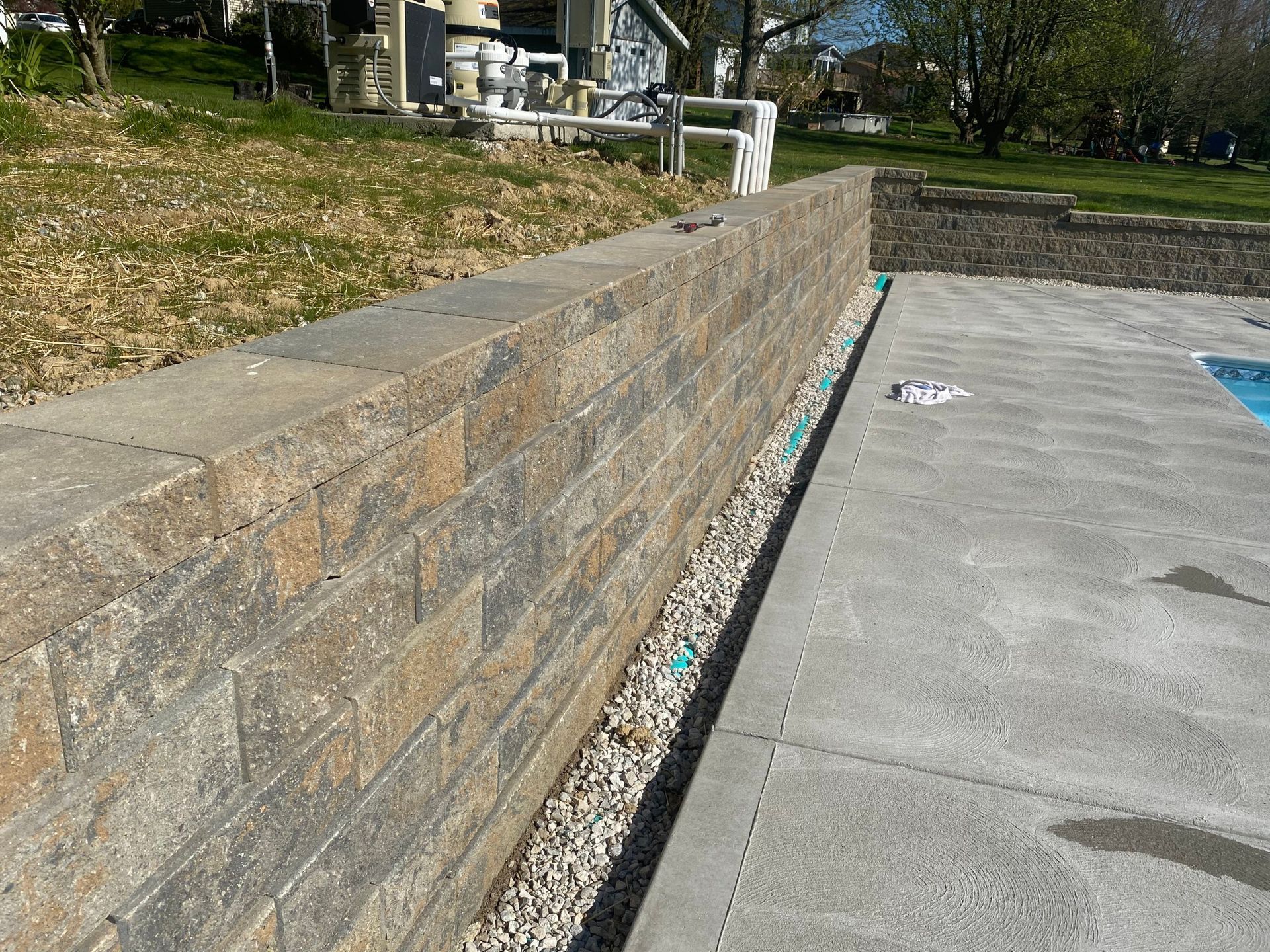 A brick wall is next to a swimming pool.