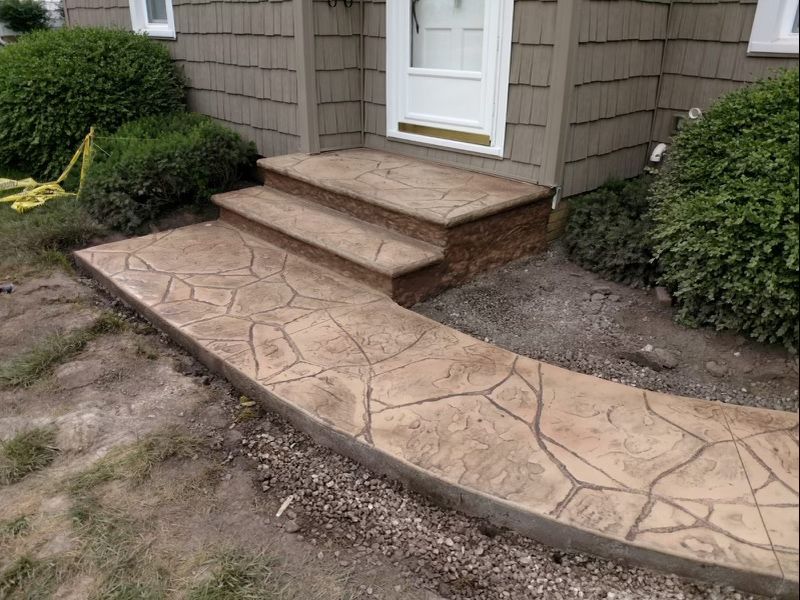 A concrete walkway leading to the front door of a house.