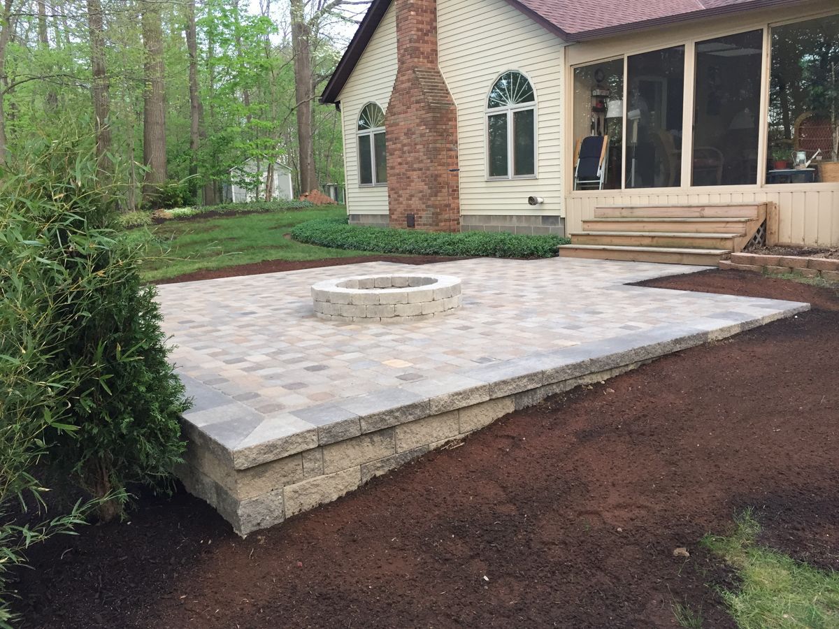 A fire pit is sitting on a patio in front of a house.