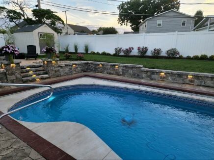 A large swimming pool is in the backyard of a house.