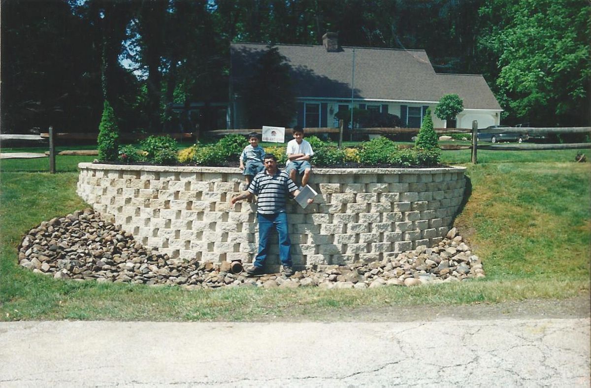 Two men standing on a stone wall in front of a house
