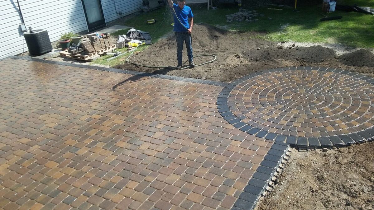 A man is standing in the middle of a brick patio.