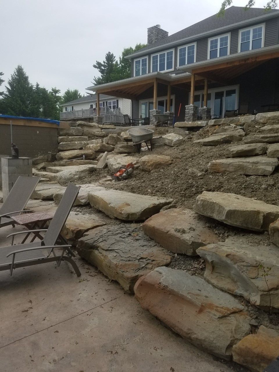 A large rock wall is being built in front of a house.