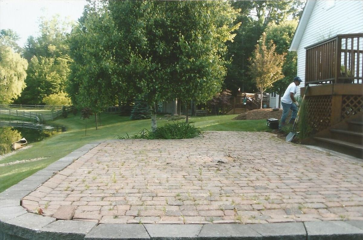 A man is standing on a brick patio in front of a house