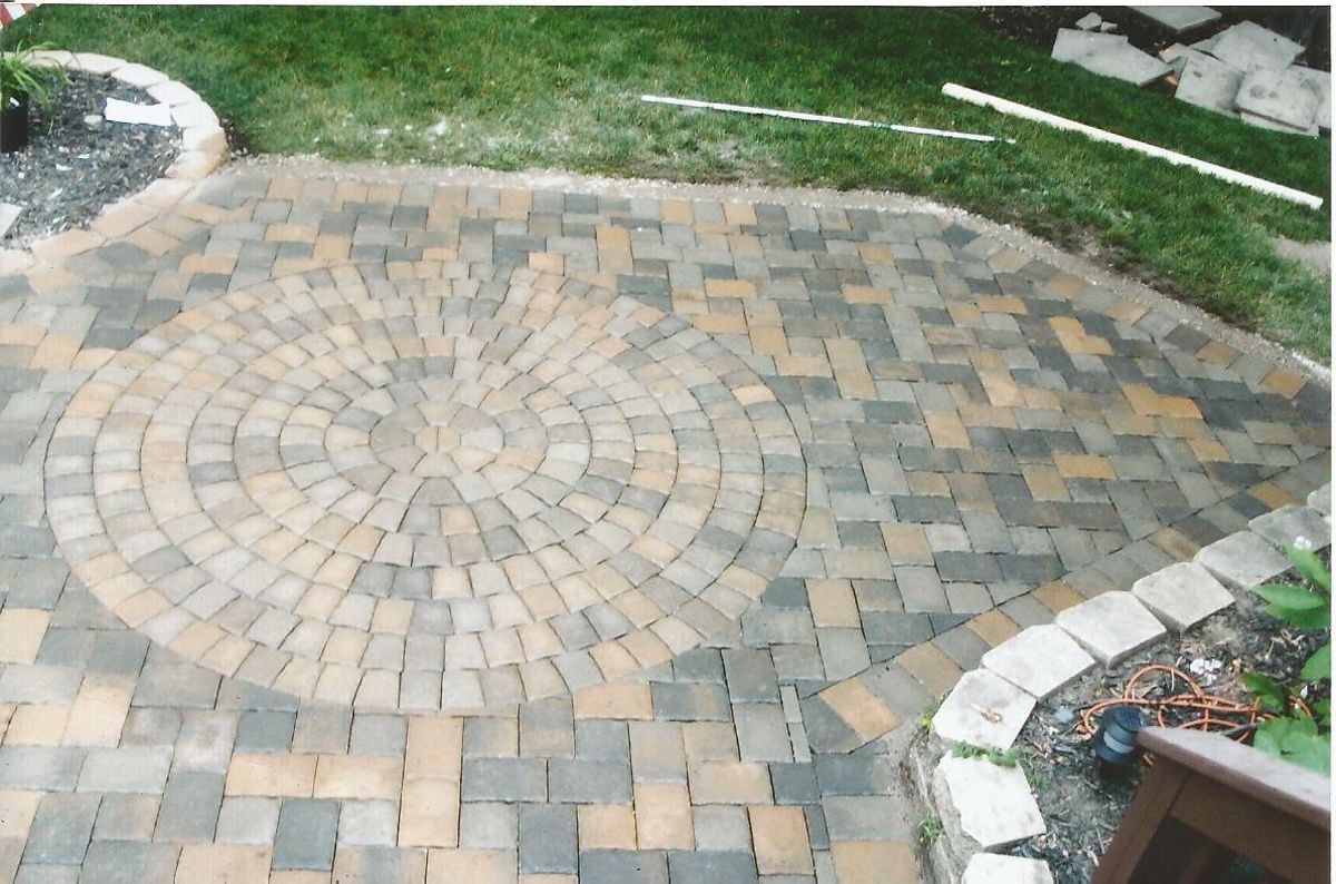 A brick patio with a circular design in the middle