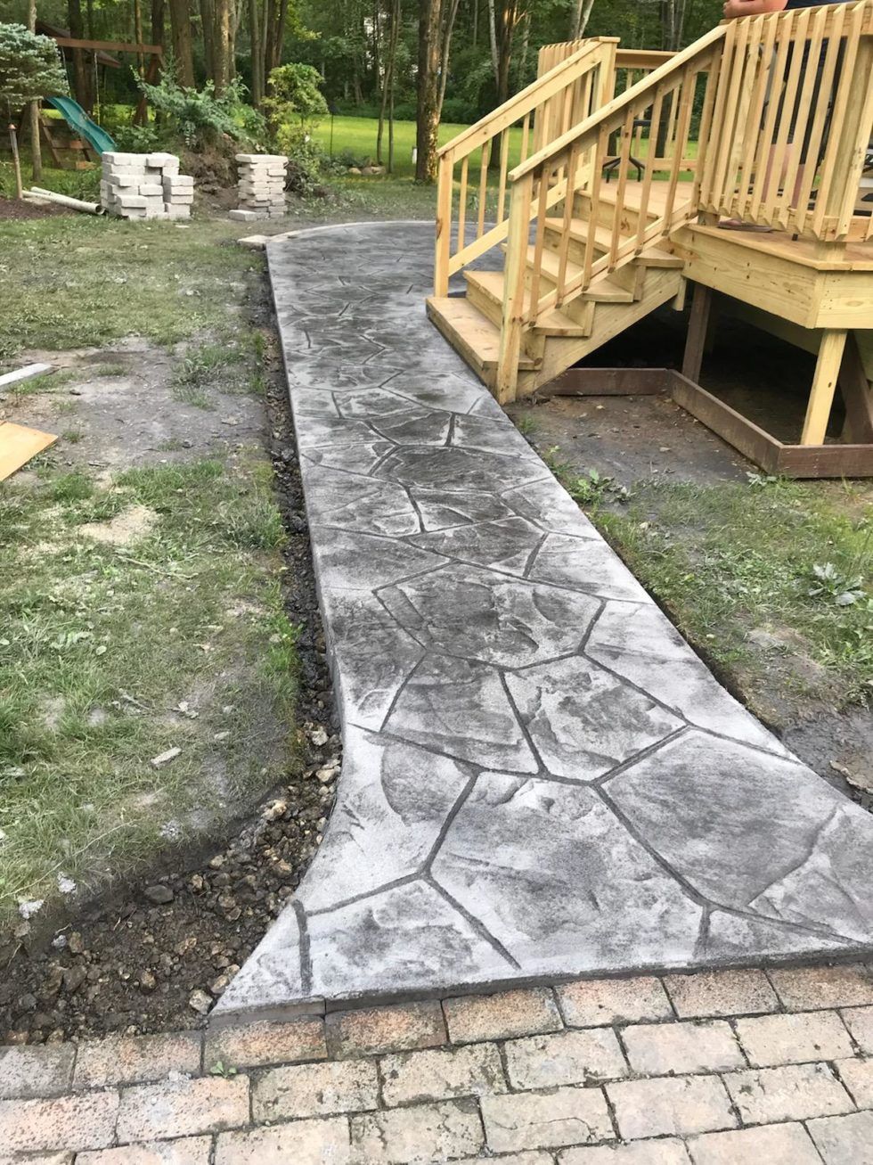 A concrete walkway leading to a wooden deck with stairs.