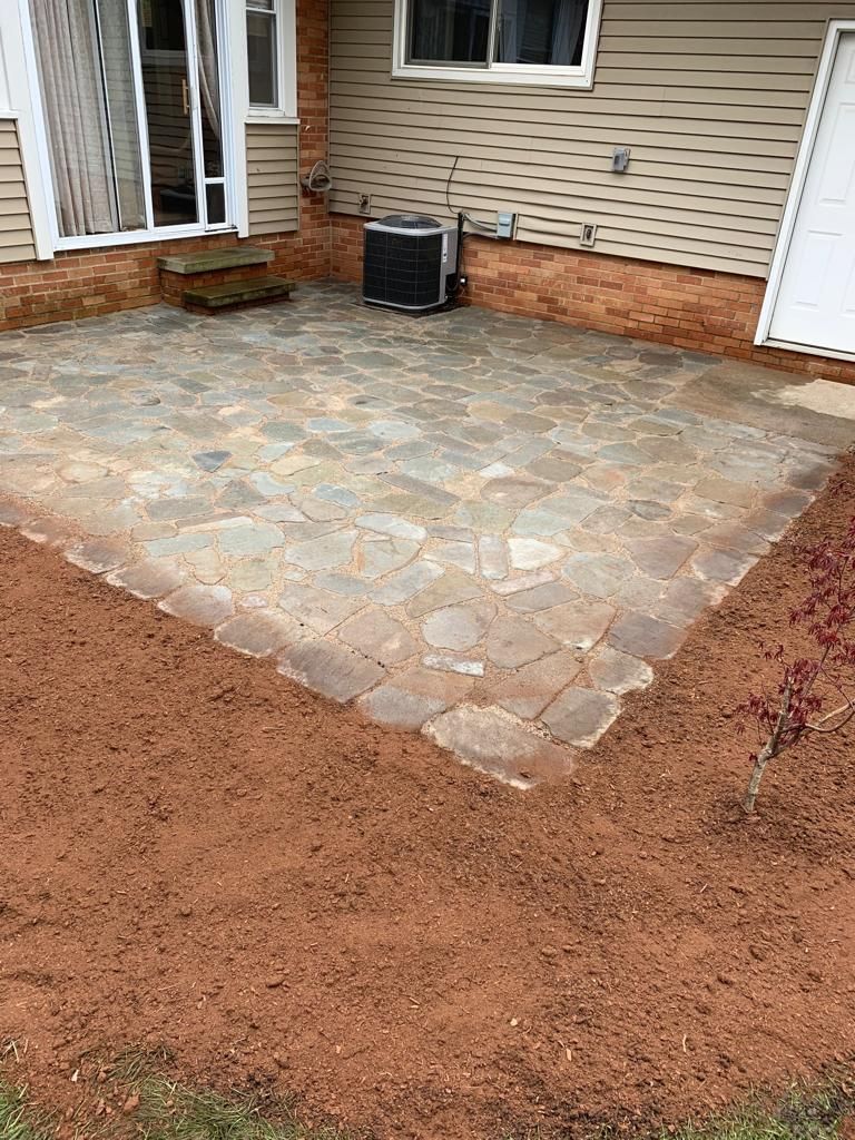 A patio with a air conditioner in the backyard of a house.