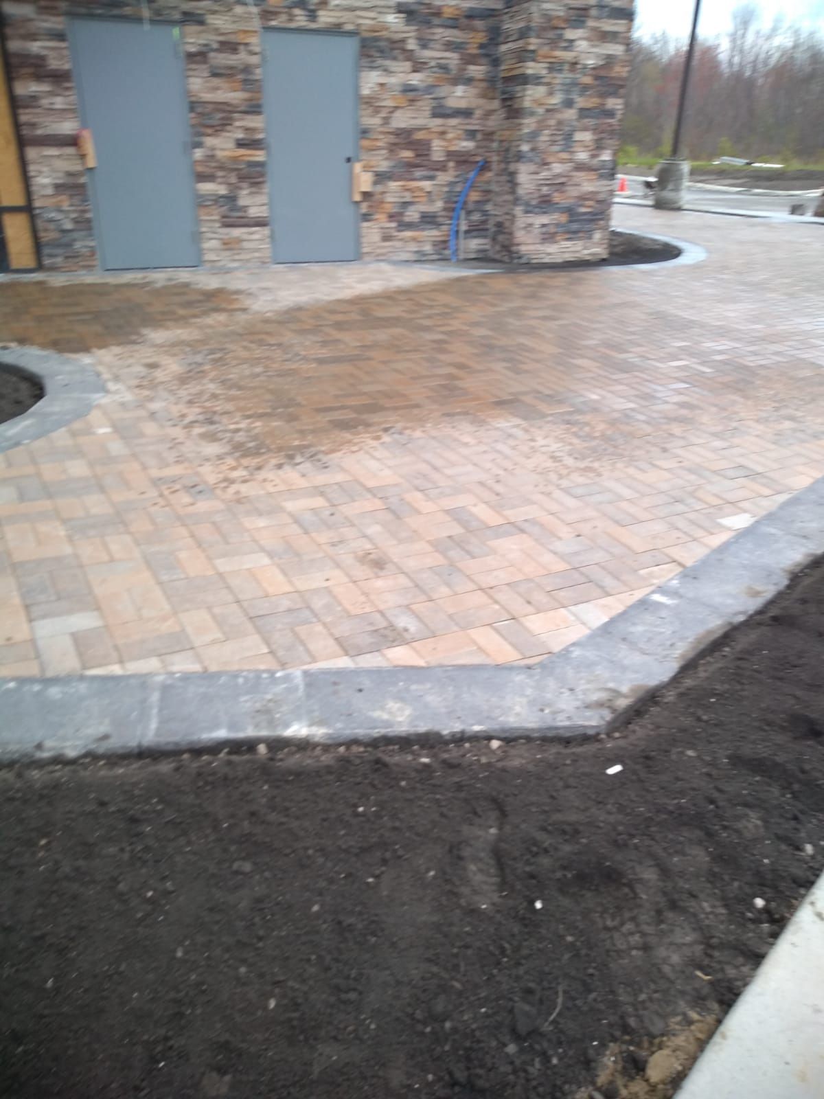 A brick walkway is being built in front of a stone building.