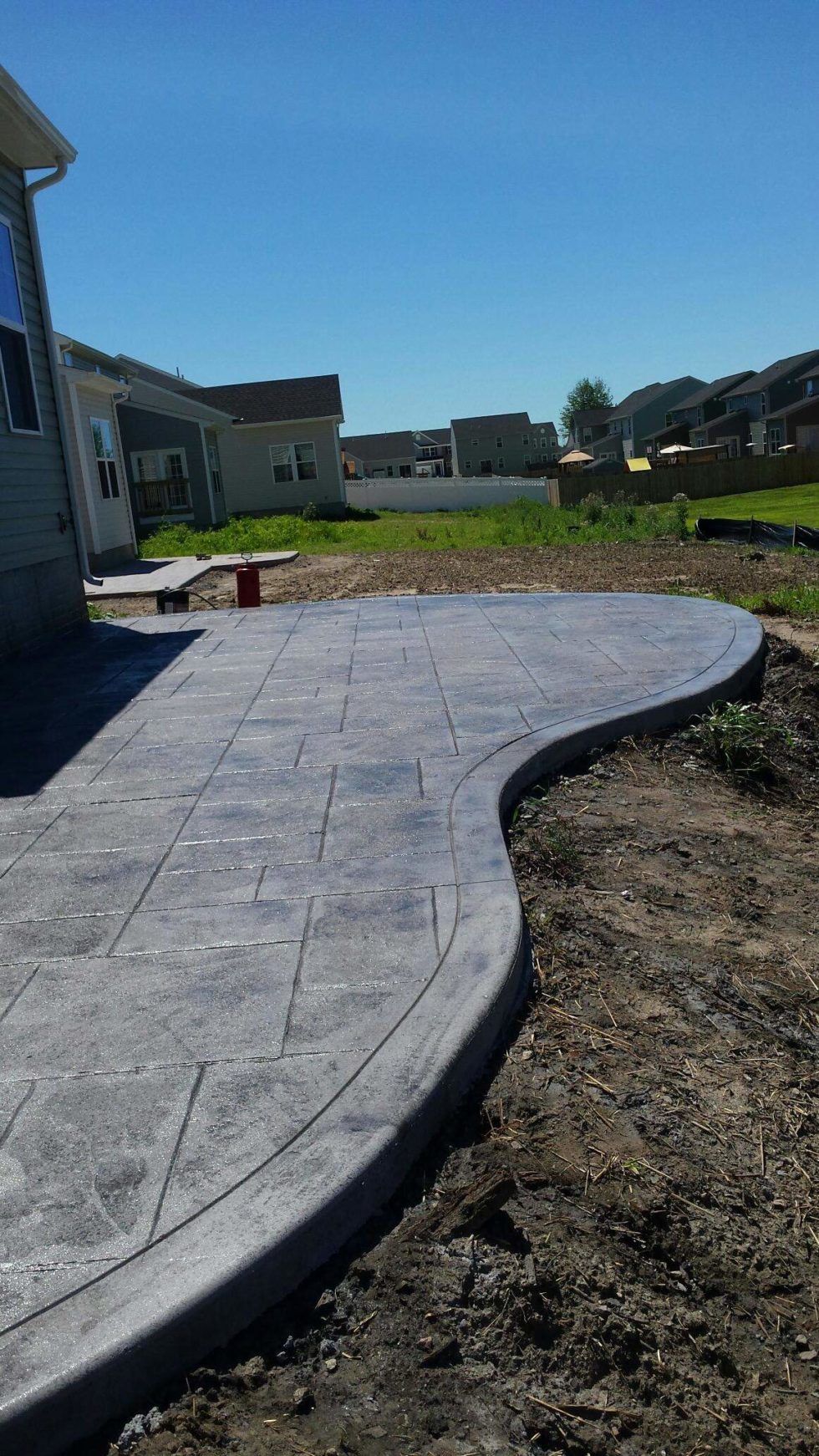A concrete walkway is being built in the backyard of a house.