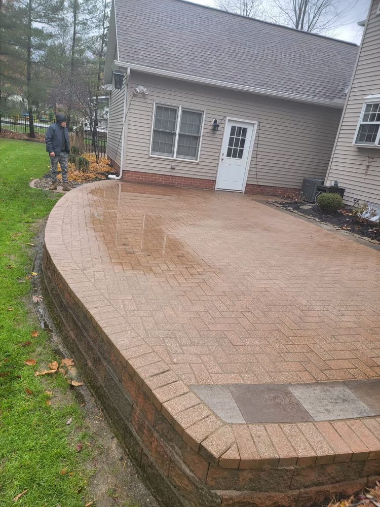 A man is standing on a brick patio in front of a house.