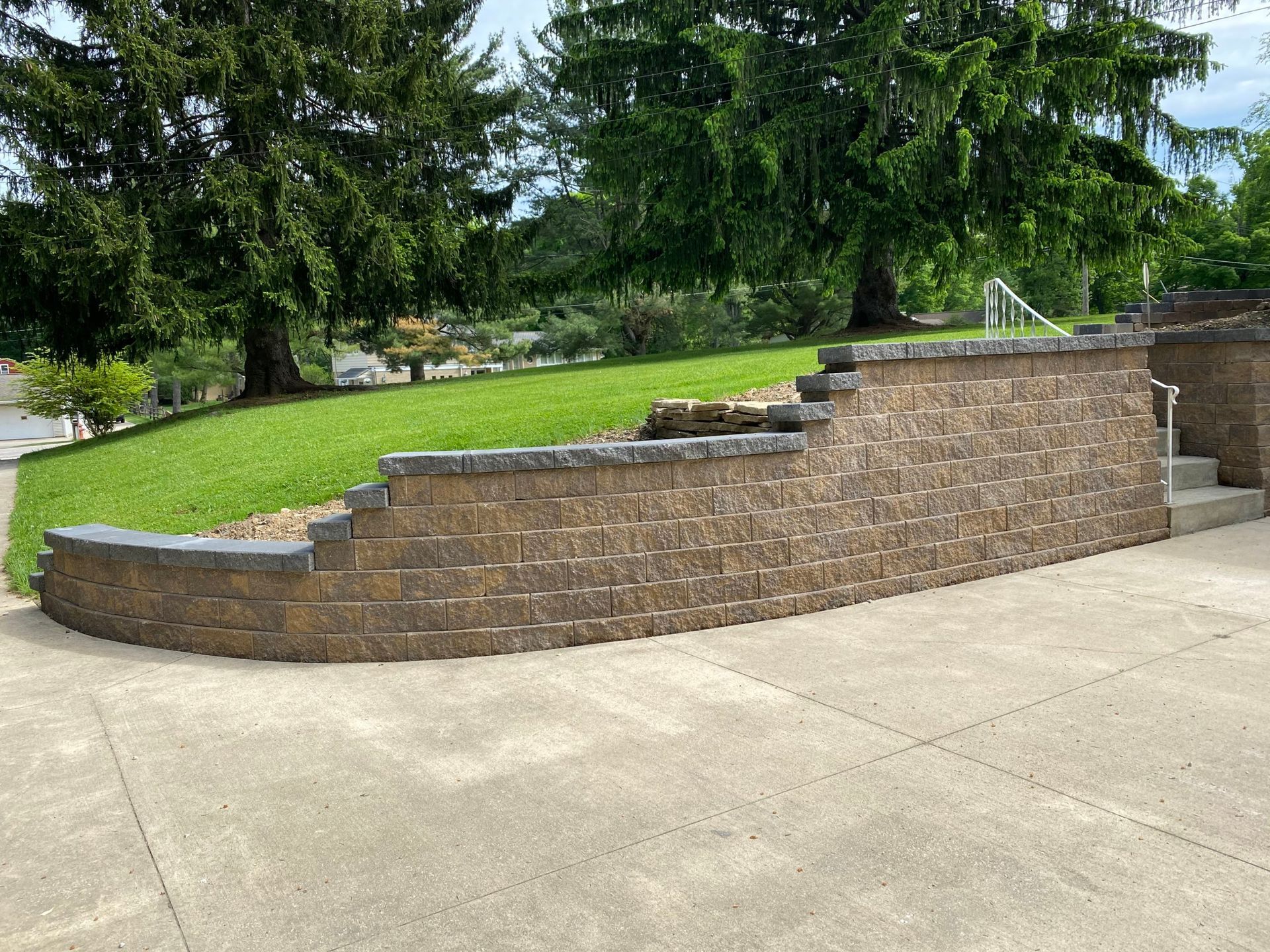 A brick wall with stairs leading up to a grassy hillside.