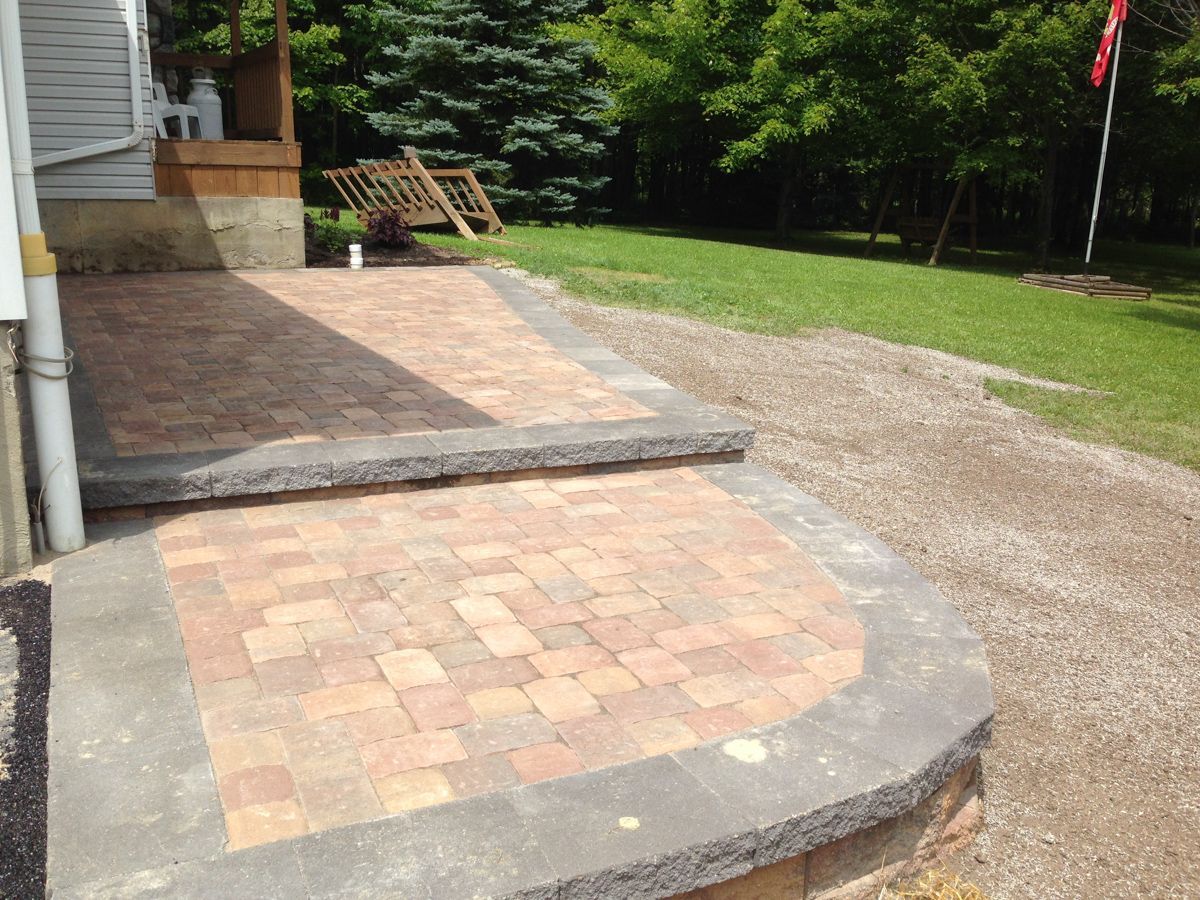A brick walkway leading to a house with a flag in the background.