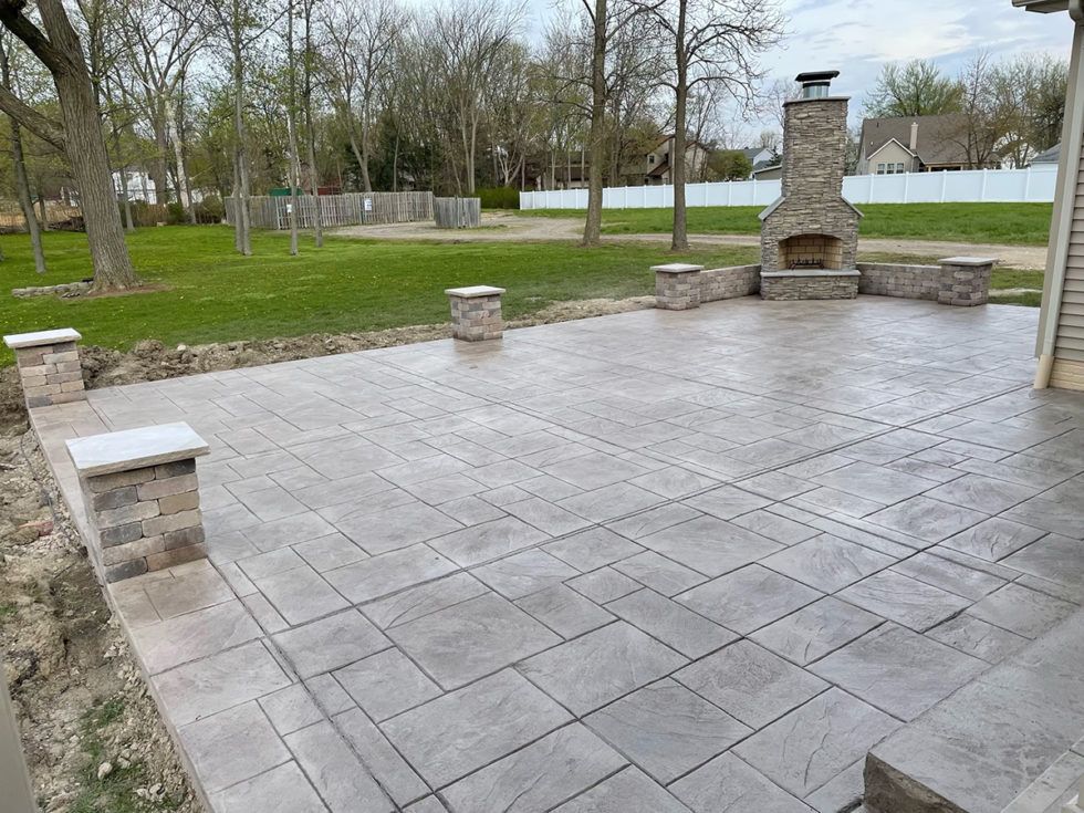 A patio with a fireplace in the middle of it.