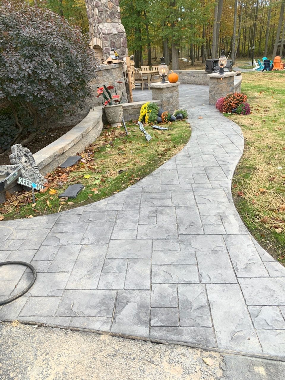 A concrete driveway with a fence in the background and trees in the background.
