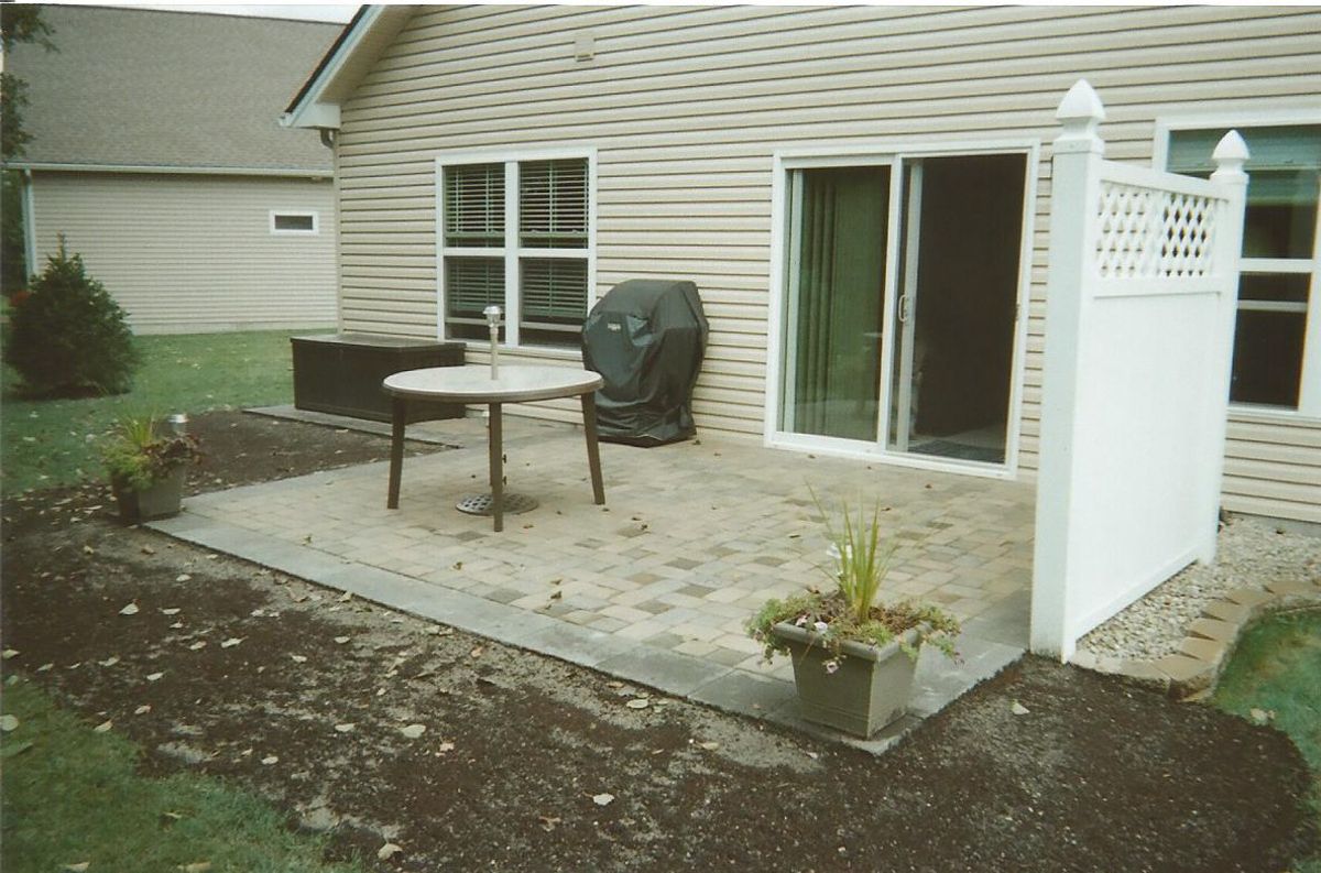A patio with a table and chairs in front of a house