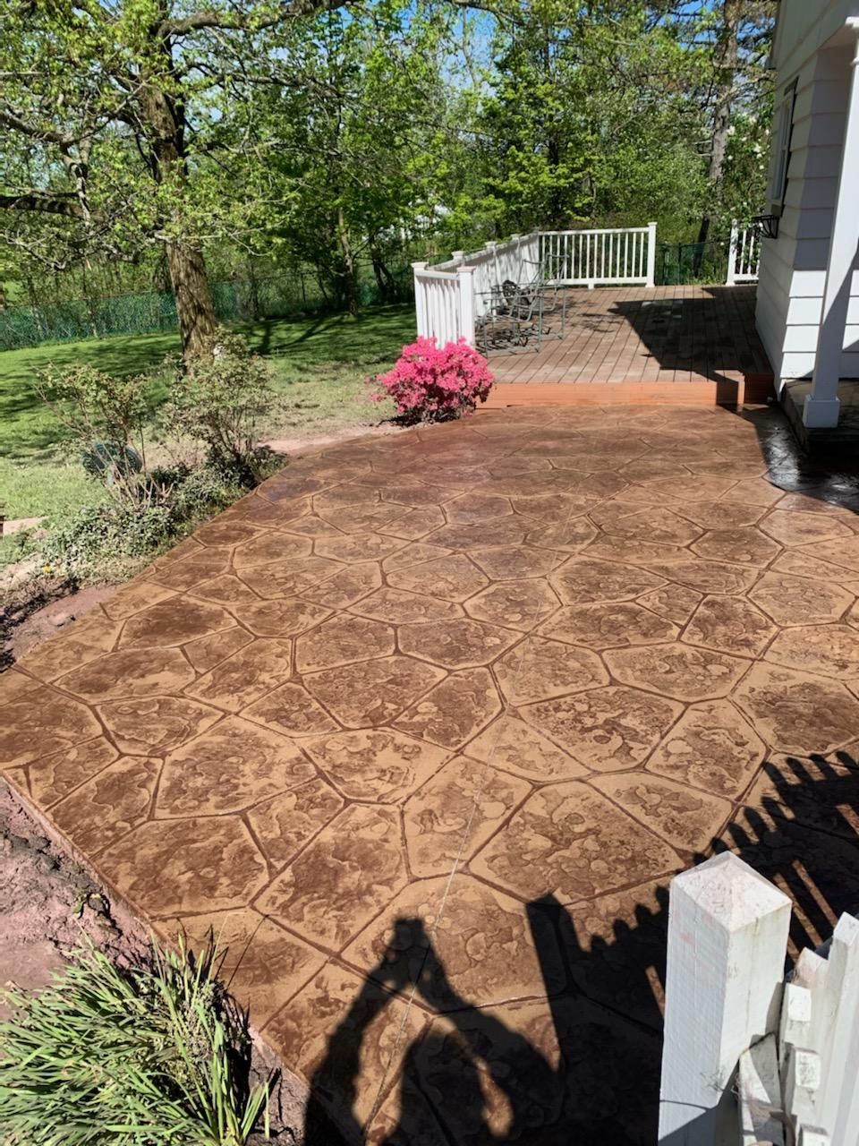 A concrete patio in front of a house with trees in the background.