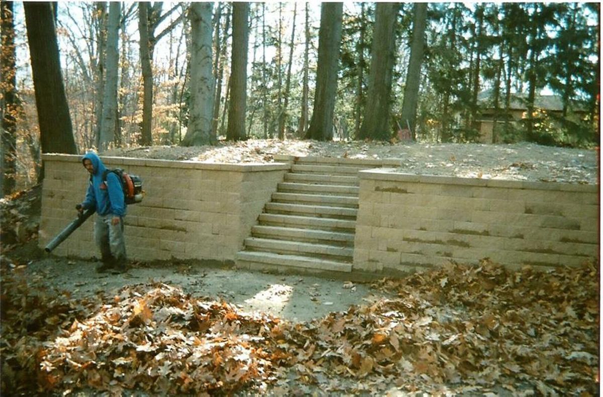 A man with a backpack is blowing leaves in the woods