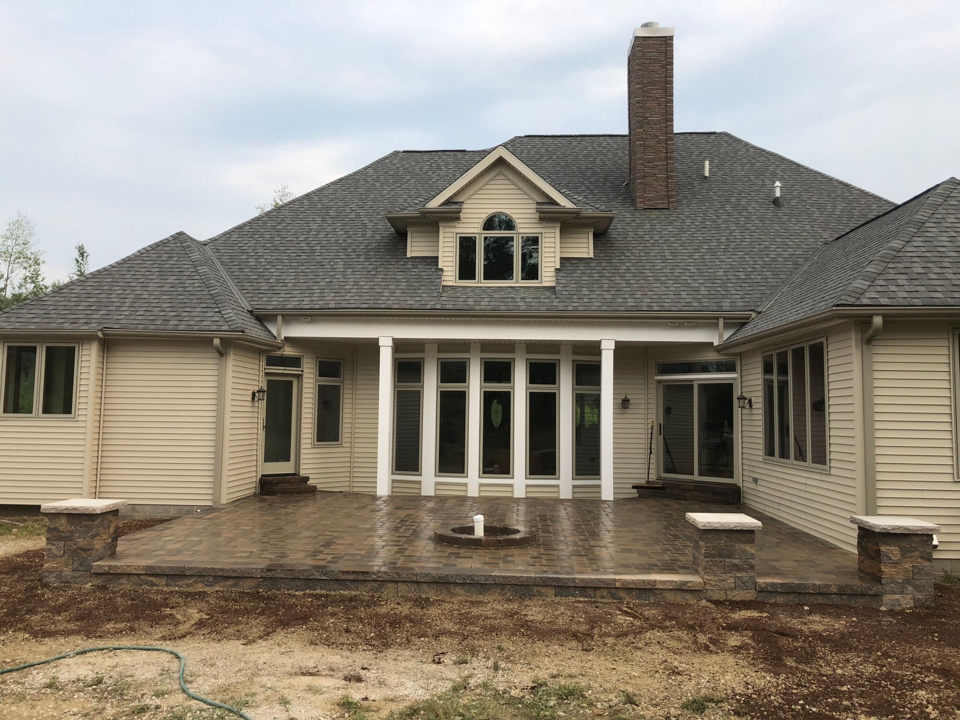 A man is standing next to a fire pit surrounded by rocks.