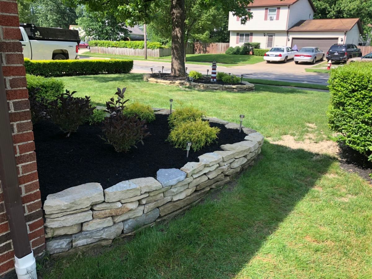 A stone wall surrounds a garden in front of a house.