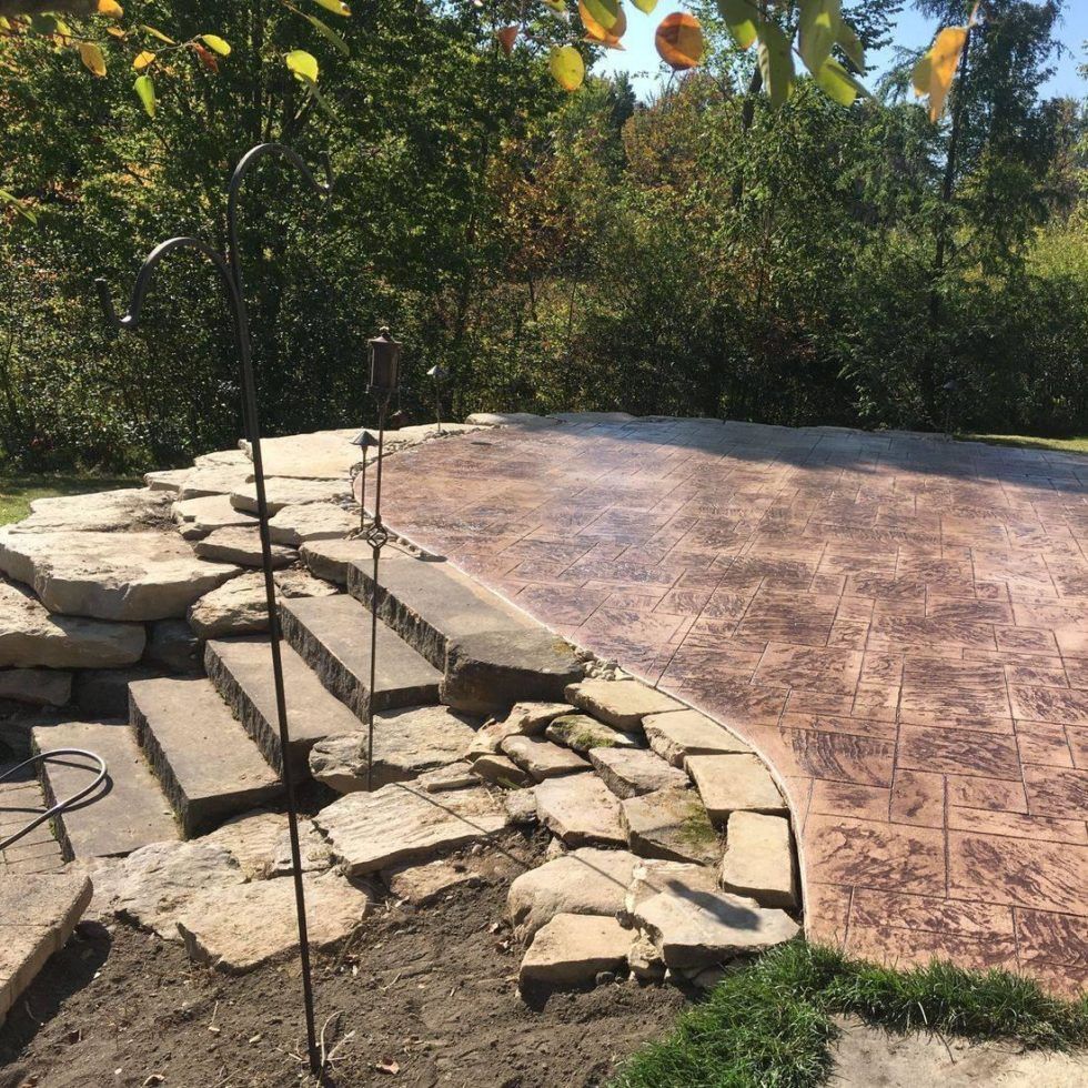 A concrete patio with steps and trees in the background