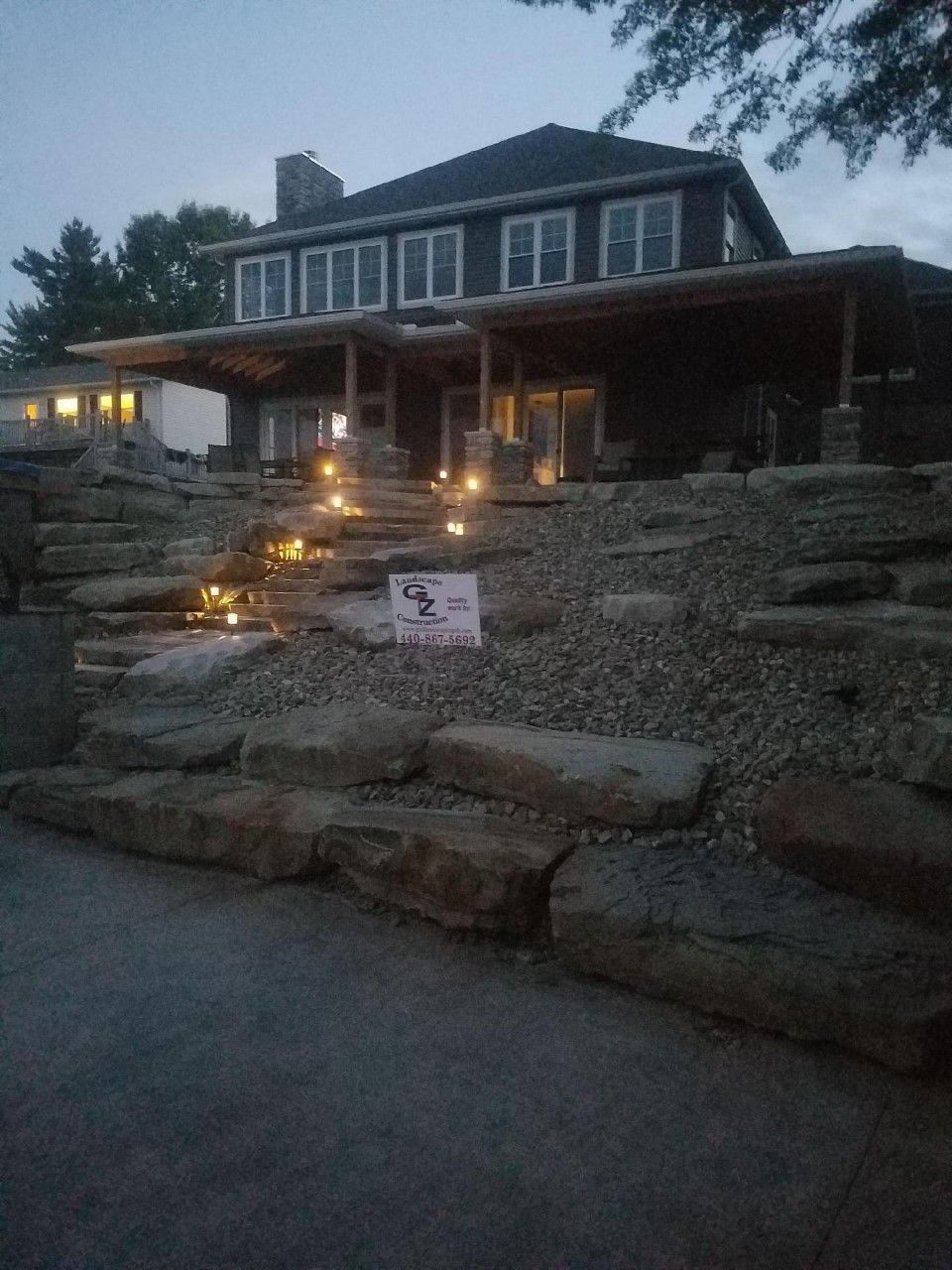 A large house is sitting on top of a rocky hill.