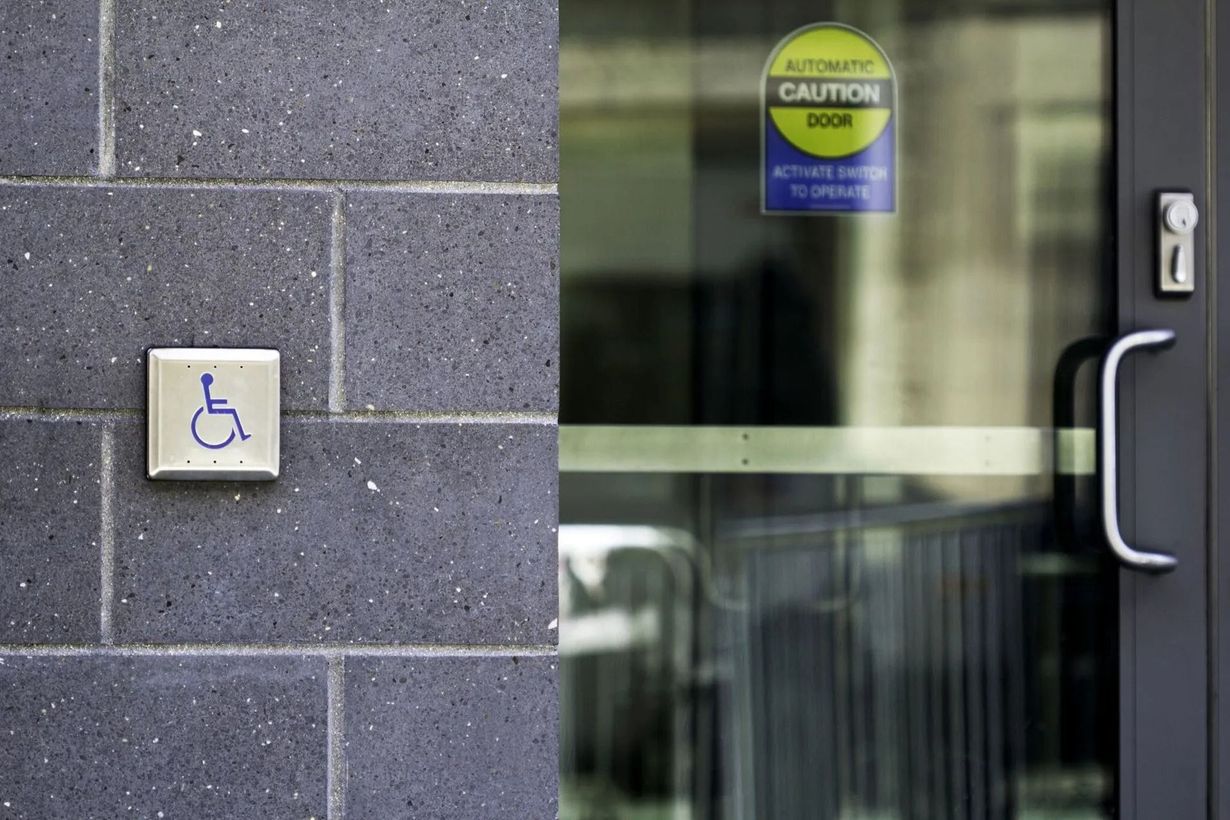 Button with wheelchair symbol next to an automatic door.