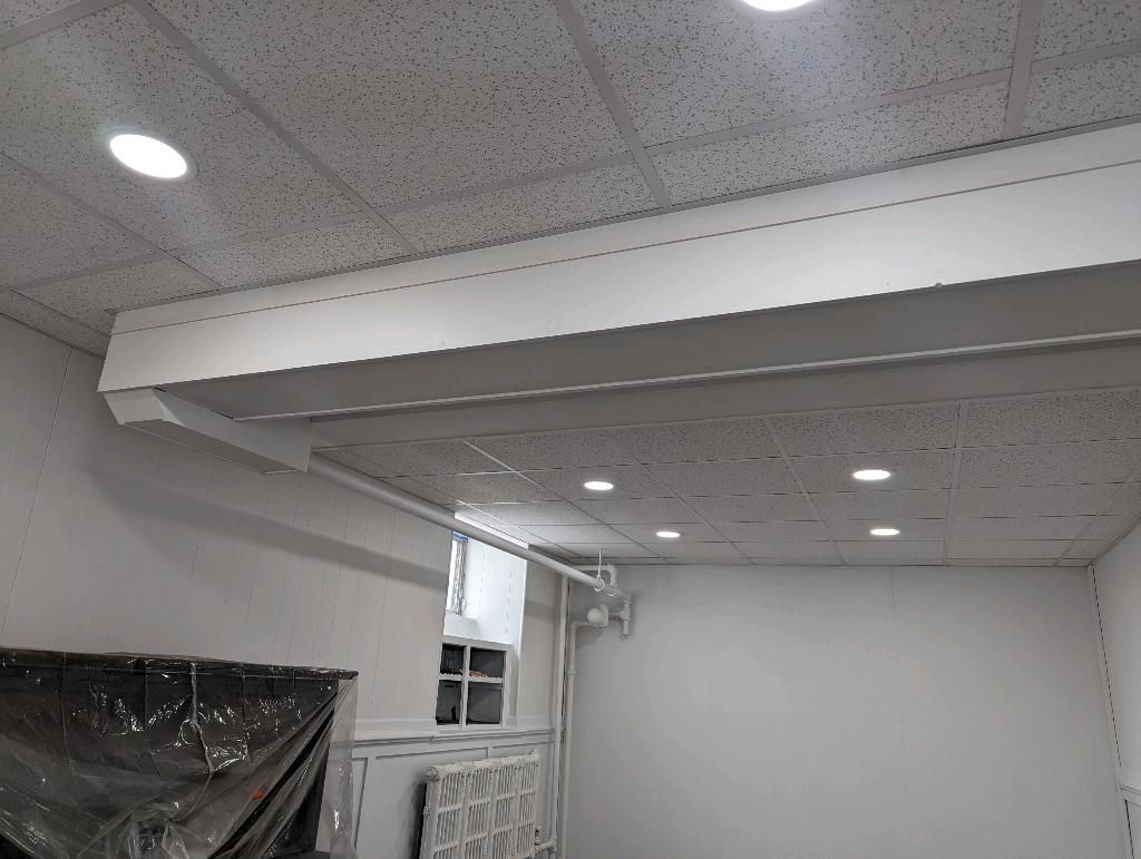 White room interior with a drop ceiling, recessed lights, and a white ledge over a window.