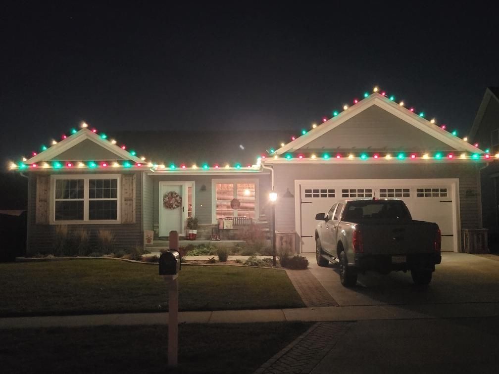 Suburban house at night decorated with multicolored Christmas lights, truck parked in the driveway