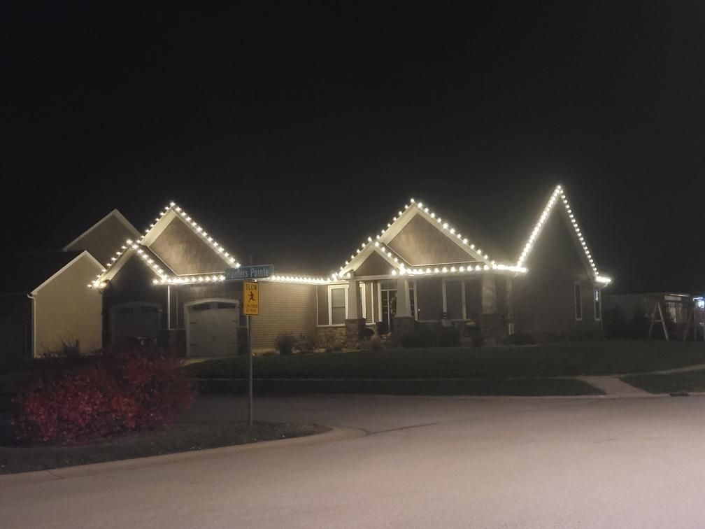 House at night outlined with white string lights, viewed from a street