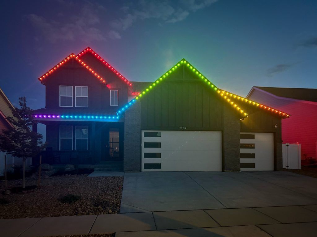House outlined with red, green, yellow, and blue holiday lights at dusk